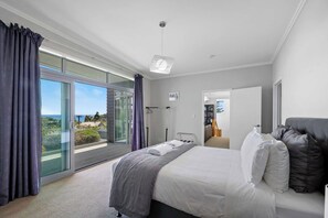 A modern bedroom with a large bed, a view of the outdoors, and a walk-in closet. - Magic on Molesworth in New Plymouth (New Plymouth)