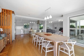 A modern kitchen with white cabinetry, a wooden dining table, and white chairs. - Magic on Molesworth in New Plymouth (New Plymouth)