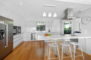 Une cuisine moderne dotée d’appareils électroménagers en acier inoxydable, d’un îlot central avec des tabourets et d’une grande fenêtre.