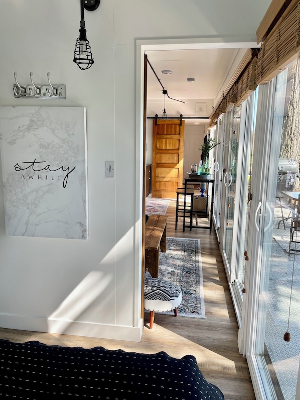 Un intĂ©rieur moderne avec une porte coulissante en bois, un coin repas avec une table et des chaises, et une grande fenĂȘtre avec des stores.
