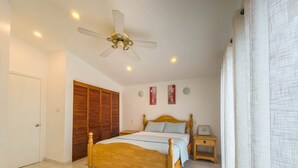 Una camera da letto con un letto di legno, una ventola a soffitto, un comodino e un armadio.