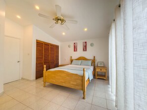 Ein Schlafzimmer mit einem hölzernen Bett, einem Deckenventilator, einem Nachttisch und einem Kleiderschrank.