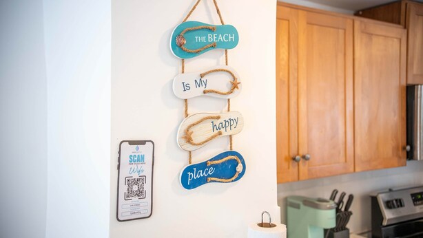 Una cucina con mobili in legno, un codice QR per l'accesso al WiFi e una decorazione a tema nautico.