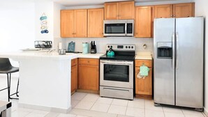 Una cucina moderna con mobili in legno, un frigorifero in acciaio inossidabile, un forno a microonde e un piano cottura.