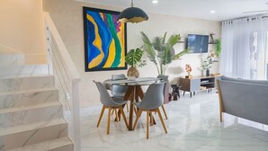 Un salon moderne comprenant un coin repas, un escalier et un grand tableau abstrait accroché au mur.