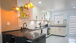 Une cuisine moderne dotée d’un îlot central, de meubles blancs et d’un éclairage suspendu.
