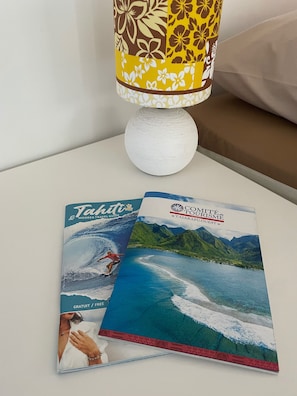 Un libro de guía de viajes y una lámpara sobre una mesita de noche.