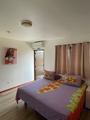 Ein Schlafzimmer mit Bett, Vorhängen, einem Bild, einer Klimaanlage und einer Tür.