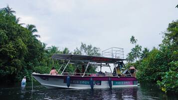 A boat with 'PARIS 2024' written on it, surrounded by lush greenery.