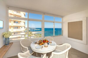 A balcony with a view of the sea, a round table with chairs, and a vase of flowers. - Marbell Center Panoramic Sea View (Marbella)