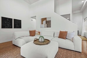 Ein modernes Wohnzimmer mit einer Eckcouch, einem Couchtisch und abstrakter Wandkunst.