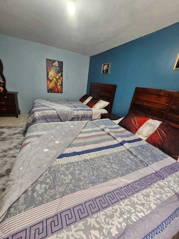 Quarto com duas camas, penteadeira e um quadro na parede.