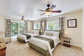 A bedroom with two beds, a ceiling fan, a small table, and a view of the outdoors. - Family Friendly Cabin w/ Meadow View, Hot Tub, Large Deck, WiFi & Private W/D (Avery)