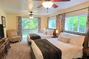 A hotel room with two beds, a ceiling fan, a TV, and a view of greenery outside. - Family Friendly Cottage w/ Meadowview, Hot Tub, Large Deck, WiFi & Private W/D (Avery)
