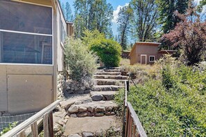 A stone staircase leading to a wooden structure surrounded by greenery. - Family Friendly Cabin w/ Meadow View, Hot Tub, Large Deck, WiFi & Private W/D (Avery)