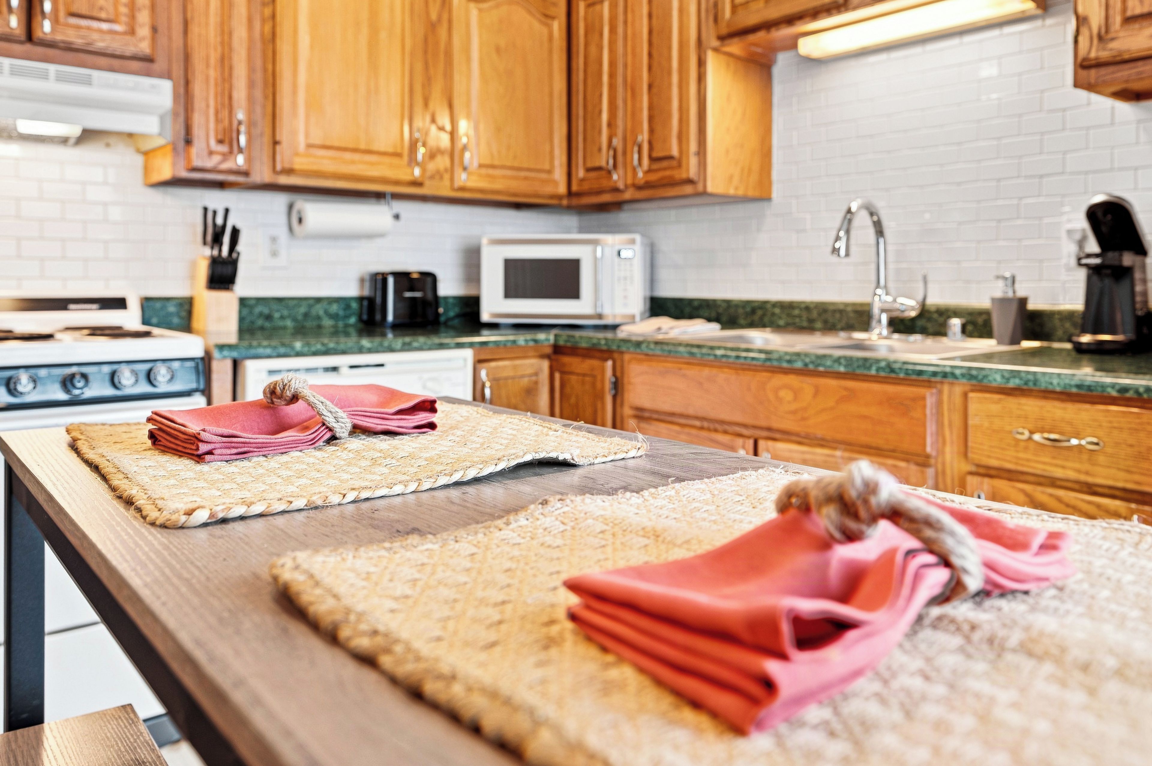 Una cocina con armarios de madera, microondas, estufa y pileta.