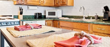 A kitchen with wooden cabinets, a microwave, a stove, and a sink.