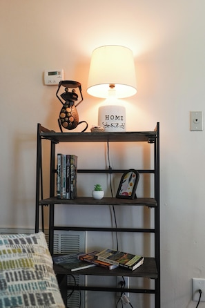 A bookshelf with books, a lamp, and a 'HOME' sign on a wall.