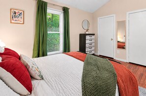 Un dormitorio con cama, cómoda, espejo y ventana con cortinas.