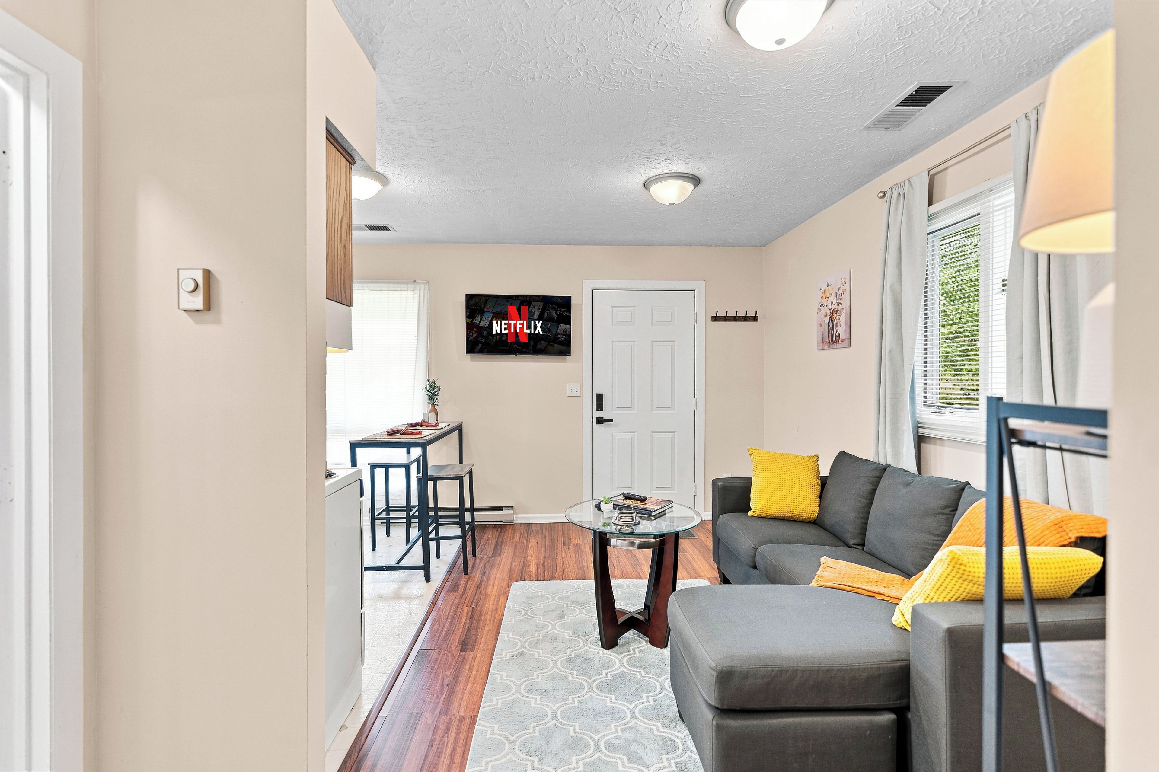 A living room with a sofa, a coffee table, and a TV mounted on the wall.