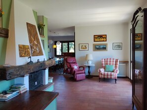 Una habitación con chimenea, un comedor y una zona de estar con una silla y una mesa.
