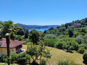 A house with a red-tiled roof, surrounded by lush greenery and a view of a lake.