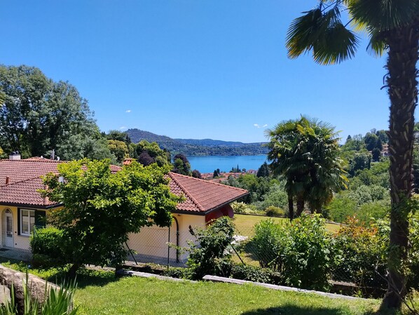 Una casa con techo de tejas rojas, rodeada de vegetación y vistas a un lago.