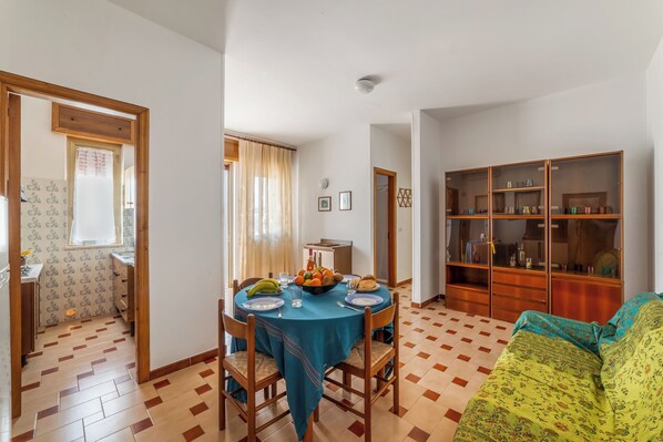 A dining area with a round table, chairs, and a buffet table with fruits and drinks. - Leuca Relax & Sea n.5C, Castrignano del Capo, Italy (Castrignano del Capo)