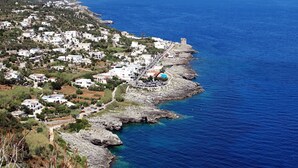 Une ville côtière aux bâtiments blancs, avec un littoral rocheux et une mer d’un bleu limpide.