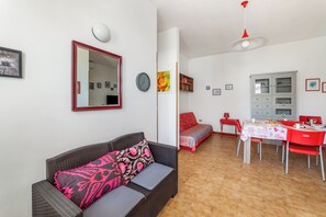 A living room with a sofa, a dining table with chairs, a cabinet, and a mirror. - Leuca Relax & Sea n.4C, Castrignano del Capo, Italy (Castrignano del Capo)