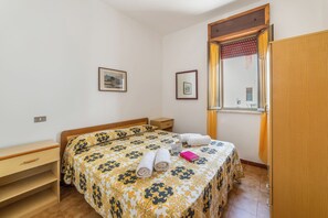 A bedroom with a bed, a nightstand, a wooden wardrobe, and a window with curtains. - Leuca Relax & Sea n.4C, Castrignano del Capo, Italy (Castrignano del Capo)