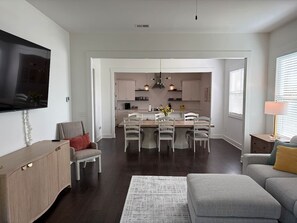 A modern living room with a flat-screen TV, a grey sofa, a wooden cabinet, and a dining area with a table and chairs. - 4 Bedroom Beauty in Vestavia, Minutes to 459, 65 (Mountain Brook)