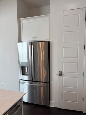 Un refrigerador de acero inoxidable con dispensador de agua, una puerta blanca y una encimera de mármol.