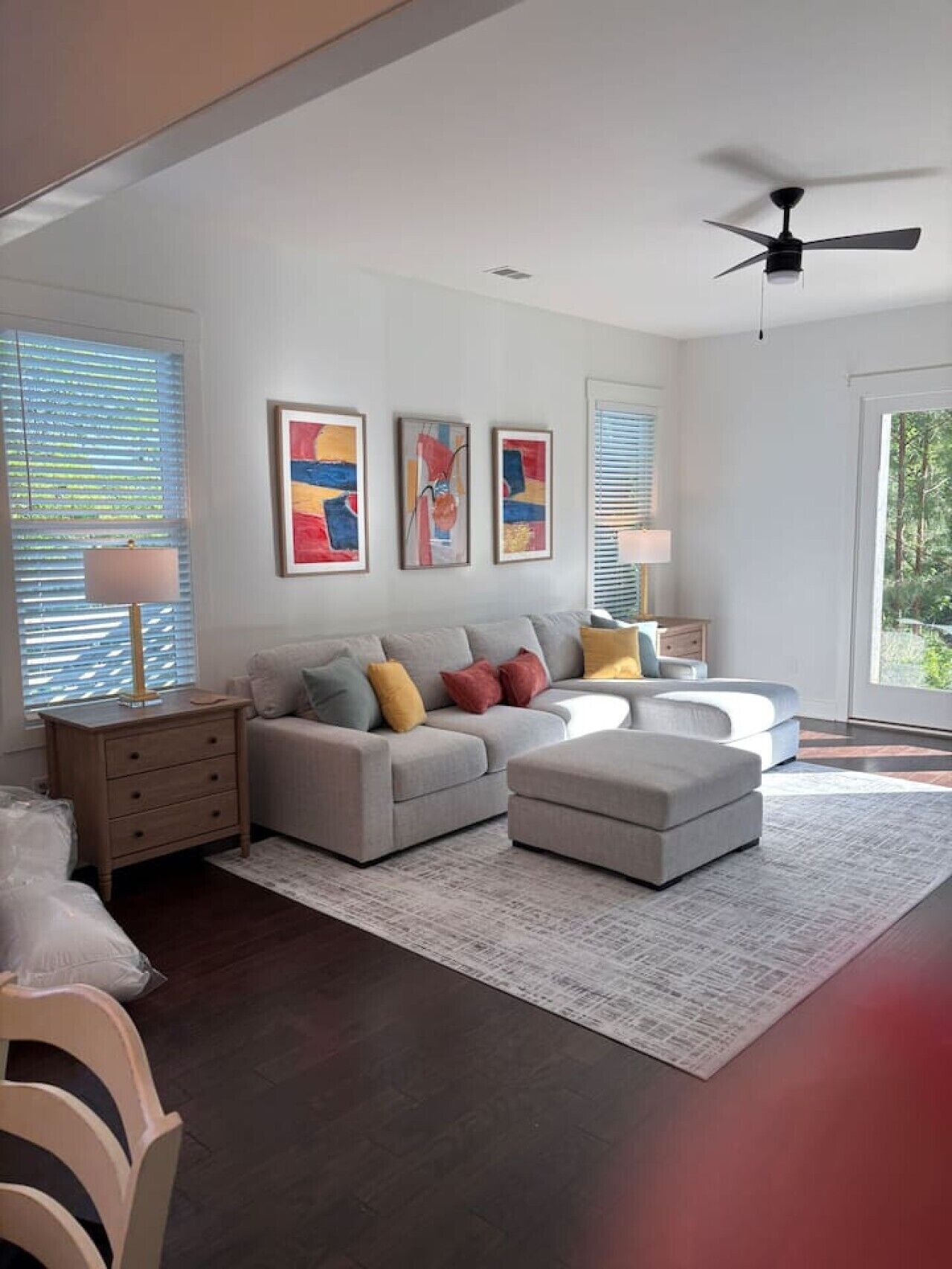 A modern living room with a sofa, ottoman, and a ceiling fan.