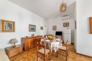 A dining area with a table set for two, wooden chairs, a white tablecloth, and a fruit bowl. - Leuca Relax&Sea n.3C, Castrignano del Capo, Italy (Castrignano del Capo)