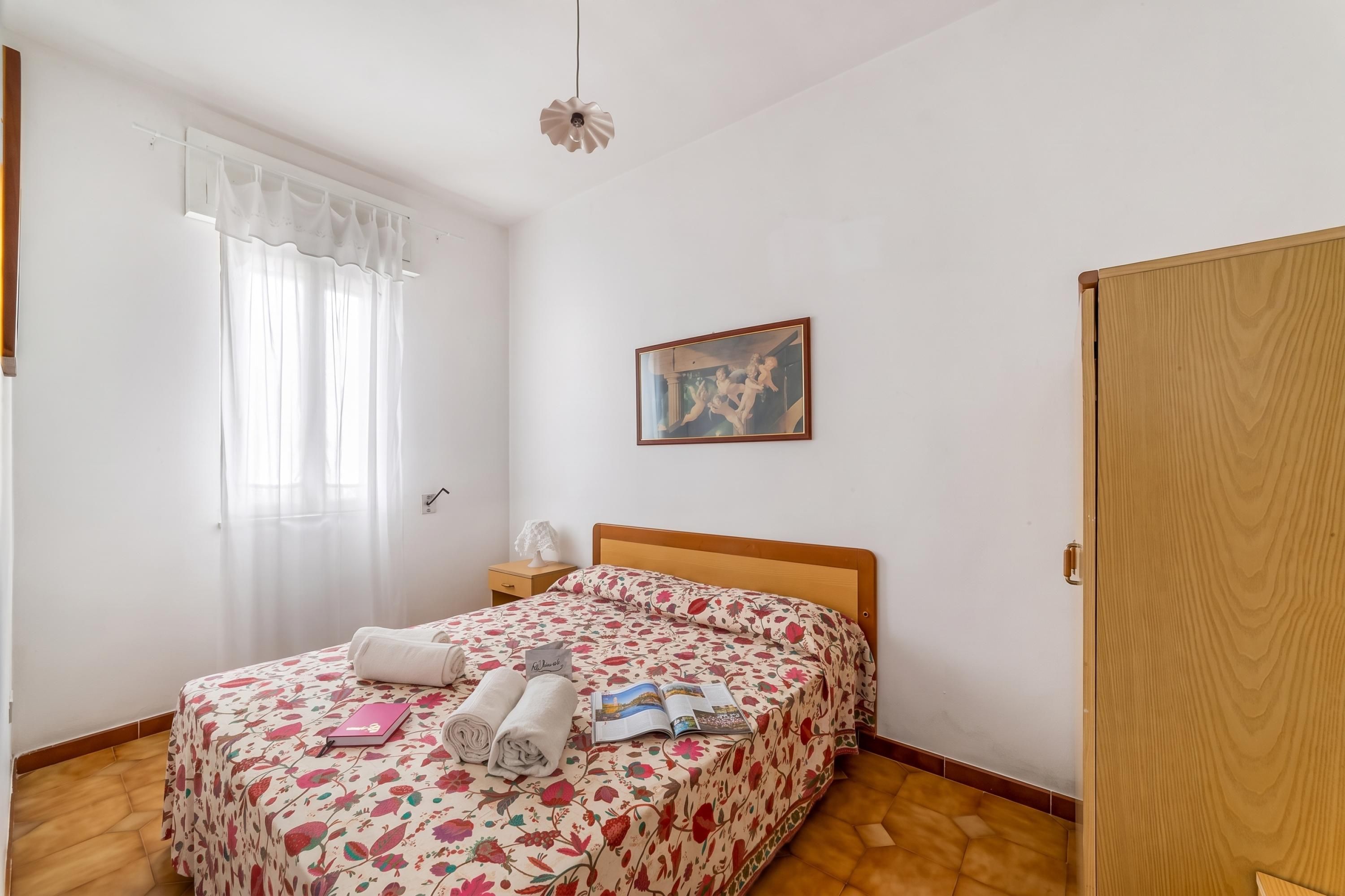 Ein Schlafzimmer mit einem Bett, einem Nachttisch, einem Gemälde und einem Holzschrank.