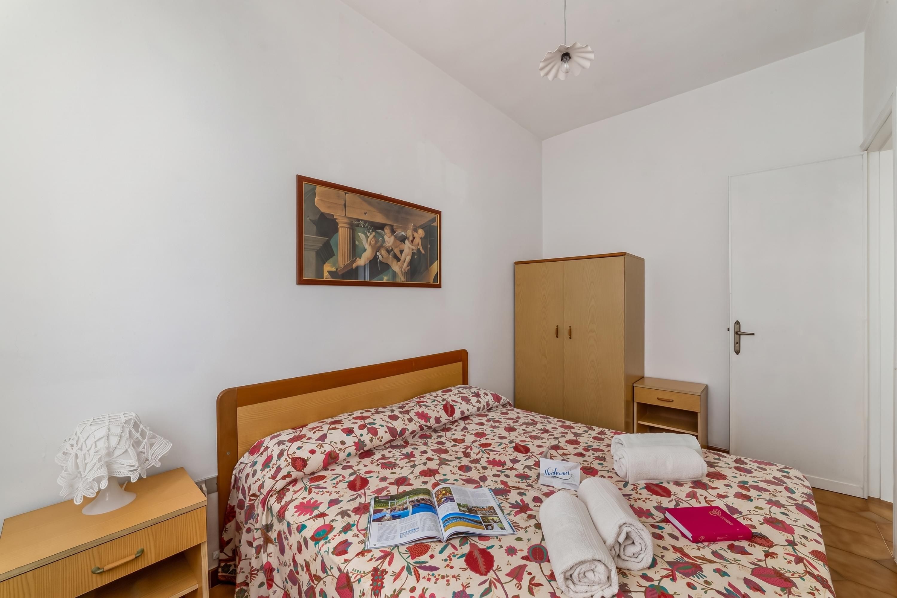 Une chambre à coucher avec un lit, une table de chevet, une armoire et un tableau au mur.