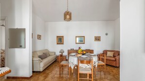 A dining area with a table set for four, surrounded by wooden chairs, a sofa, and a brown leather couch. - Leuca Relax&Sea n.3C, Castrignano del Capo, Italy (Castrignano del Capo)