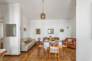 A dining area with a table set for four, surrounded by wooden chairs, a sofa, and a brown leather couch. - Leuca Relax&Sea n.3C, Castrignano del Capo, Italy (Castrignano del Capo)
