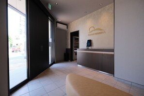 Zona de recepción con mostrador, teléfono en la pared y puerta de acceso al exterior.