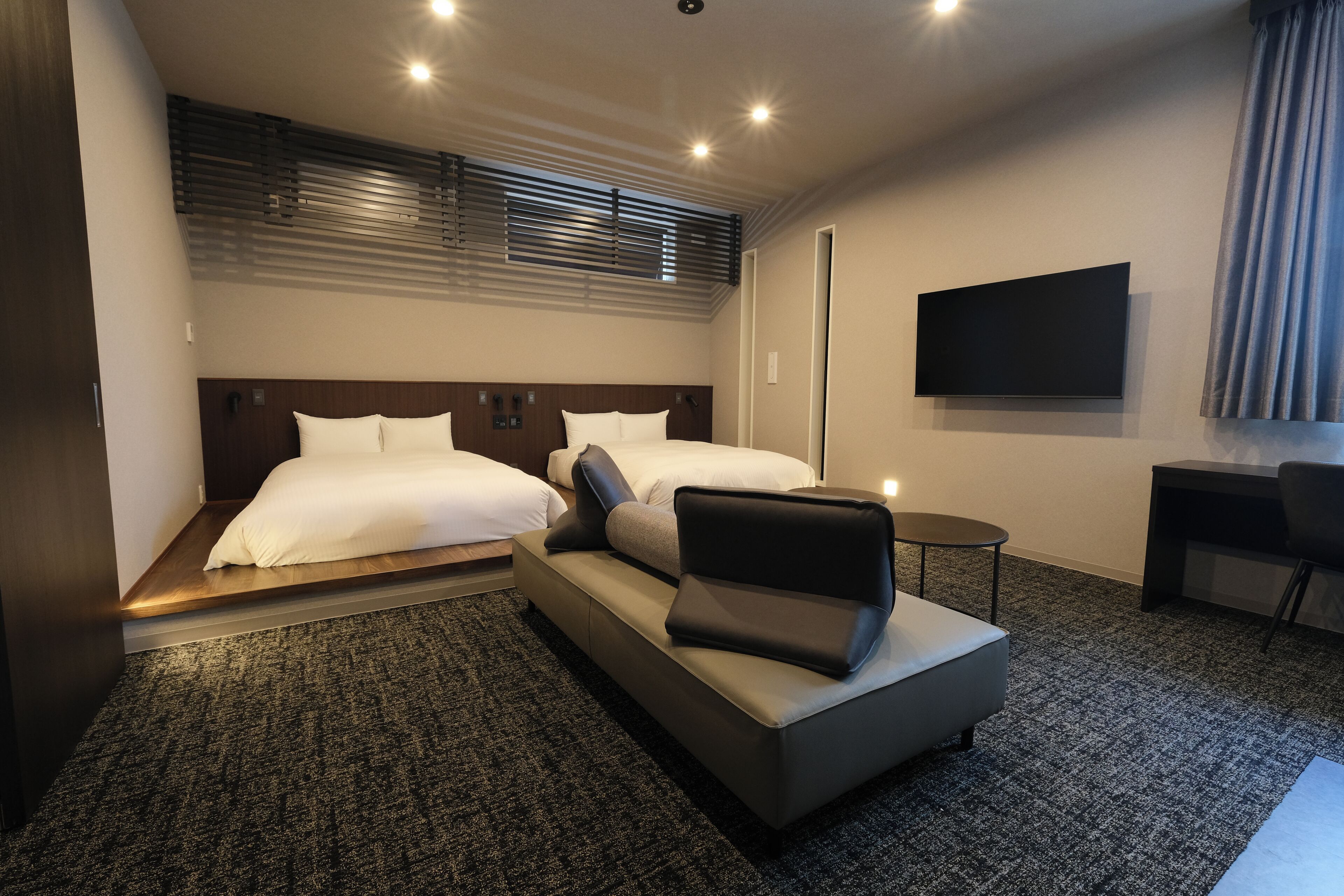 Ein Hotelzimmer mit Bett, einer Sitzecke, einem Schreibtisch und einem Fernseher.