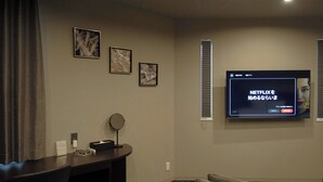 A room with a TV mounted on the wall, a small table with a mirror, and framed pictures on the wall. - Gran Marina (Osaka)