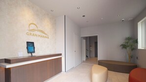 A reception area with a reception desk, a wall-mounted screen, a seating area, and a potted plant. - Gran Marina (Osaka)