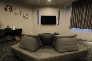 Una sala de estar con un sofá modular, un televisor de pantalla plana y obras de arte enmarcadas en la pared.