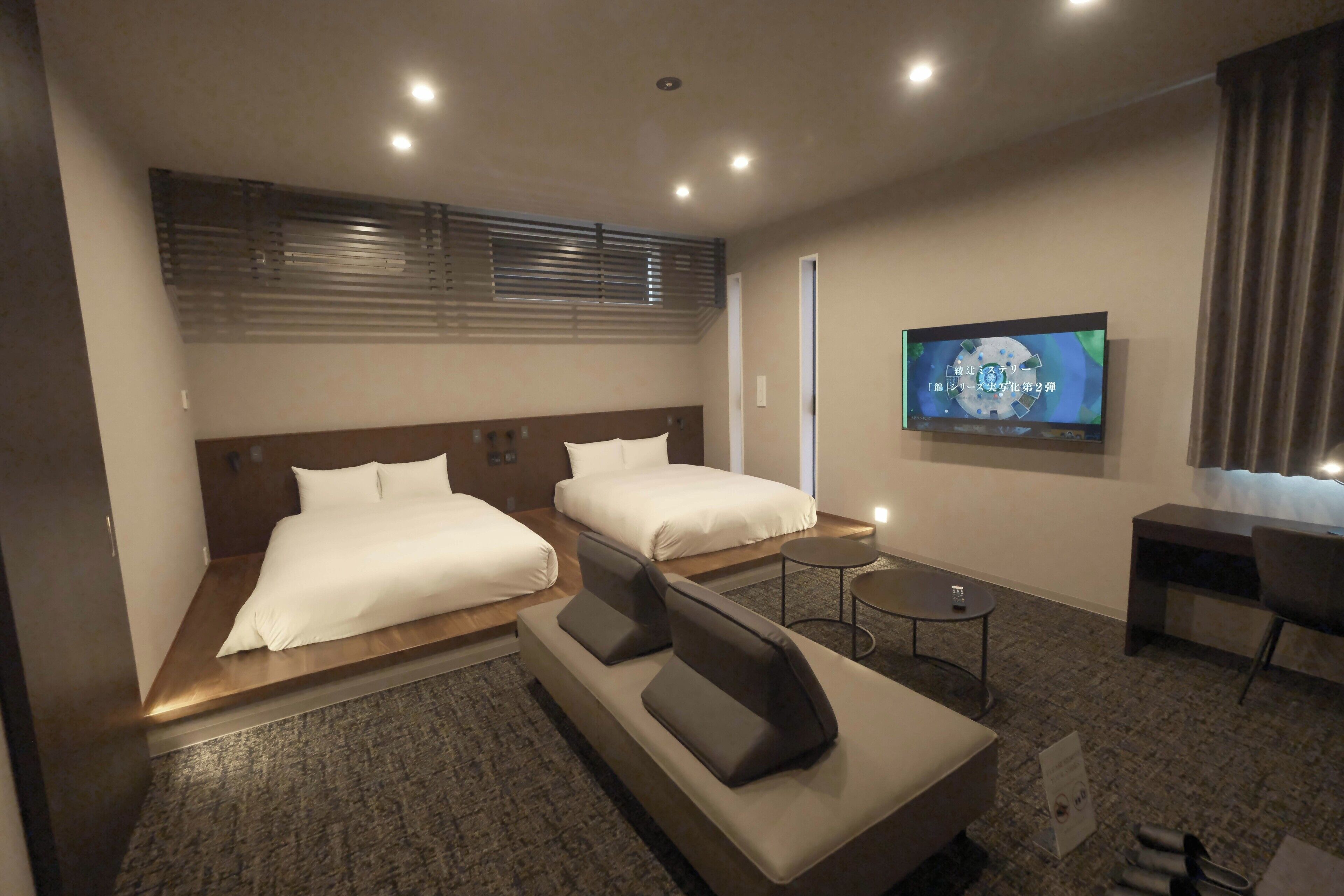 Une chambre d’hôtel avec deux lits, un canapé, une télévision, un bureau et une petite table.