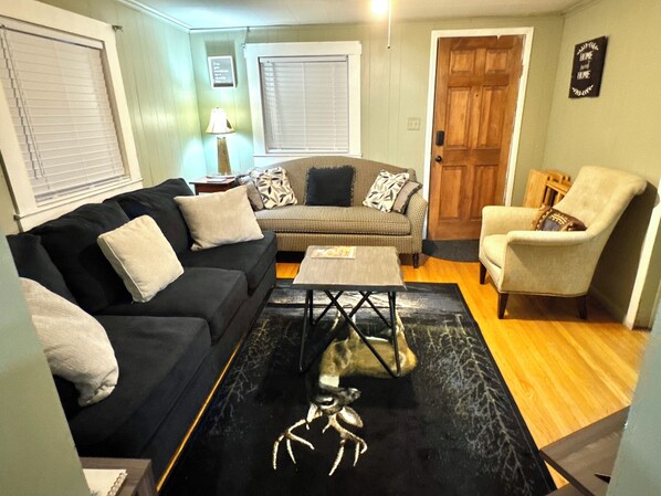 A living room with a black sofa, a patterned sofa, a wooden coffee table, and a beige armchair. - ATV Trails and Skiing! Perfect 3-bedroom house in Rock (Rock)