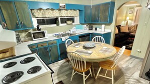 Une cuisine compacte comprenant un coin repas, une cuisinière et un ventilateur de plafond.