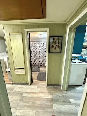 A hallway with a patterned wall, a door leading to a room, and a kitchen area with appliances. - ATV Trails and Skiing! Perfect 3-bedroom house in Rock (Rock)