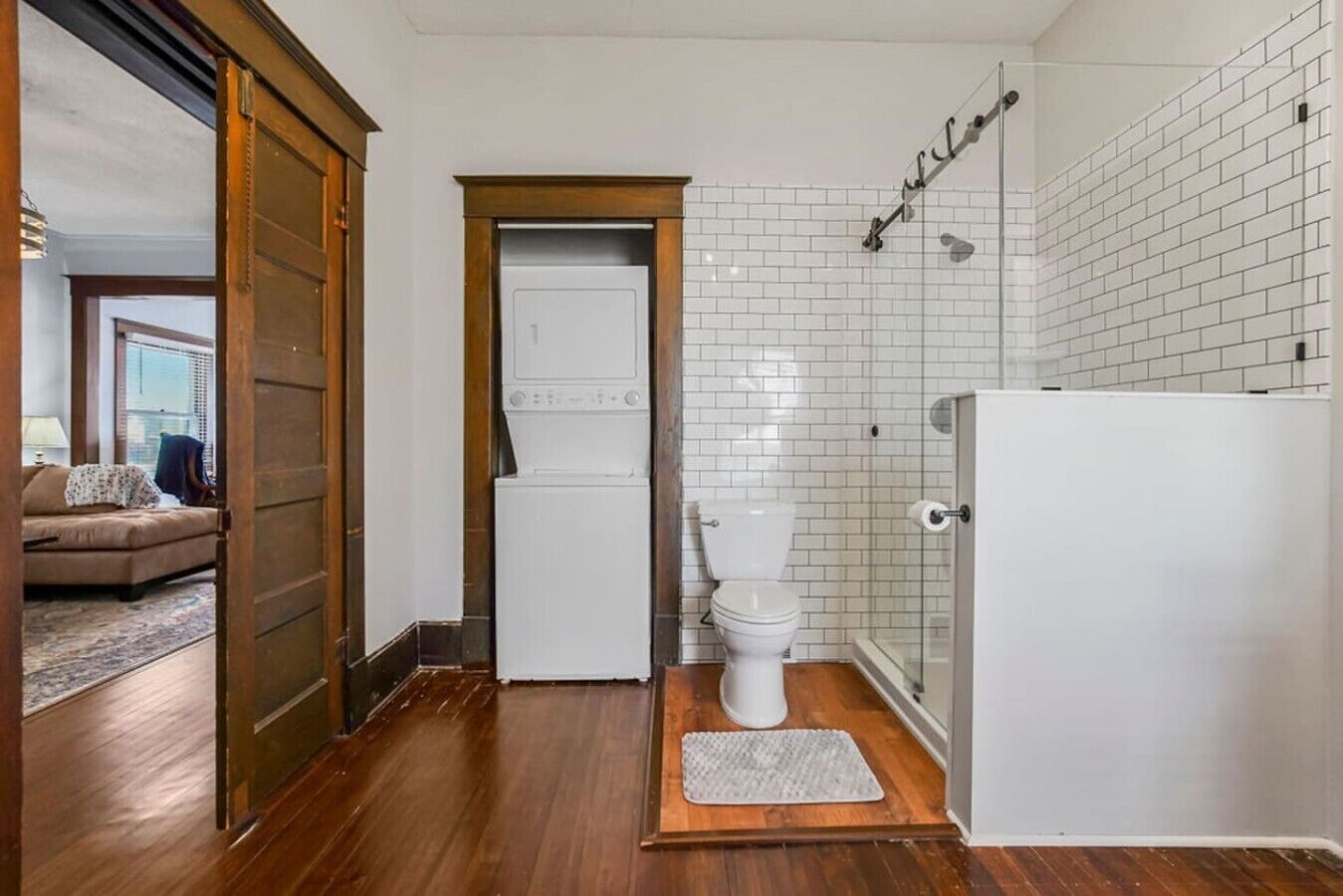A compact bathroom with a toilet, a shower, and a washing machine.