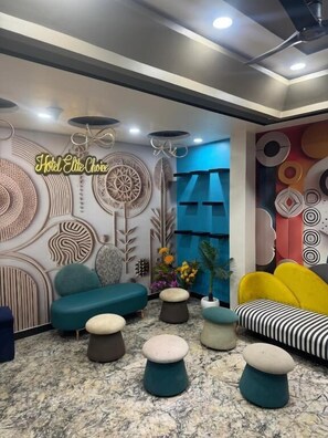 Uma área de estar moderna com diversas opções de assento, painéis decorativos na parede e teto com iluminação embutida.